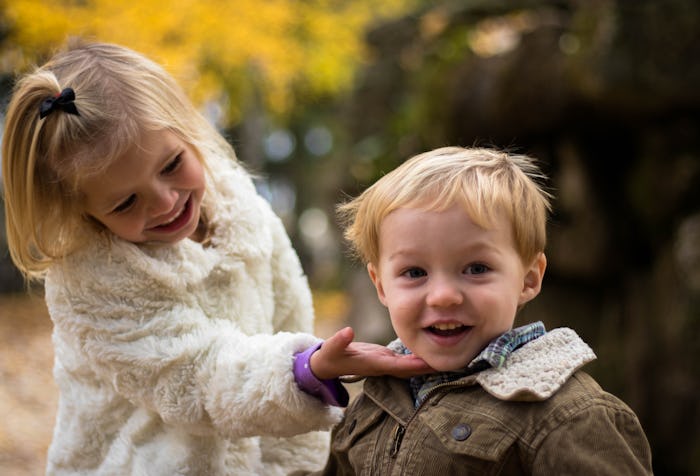 A brother and a sister standing on a street