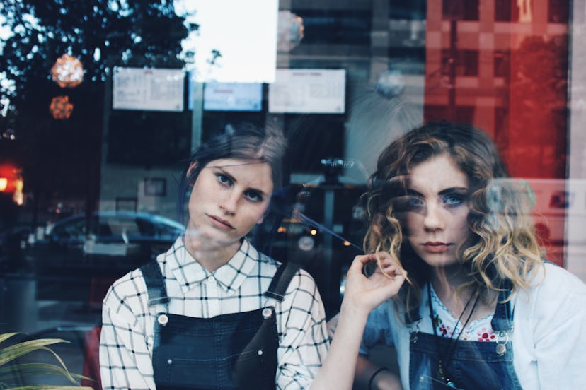 Two girls with serious faces looking through window