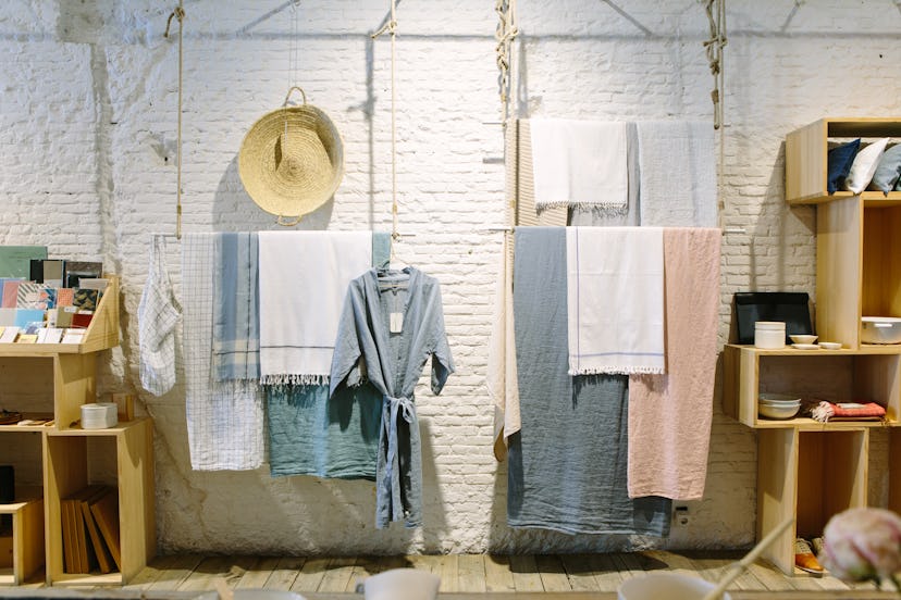 A bunch of towels and a bathroom robe hang on a wall