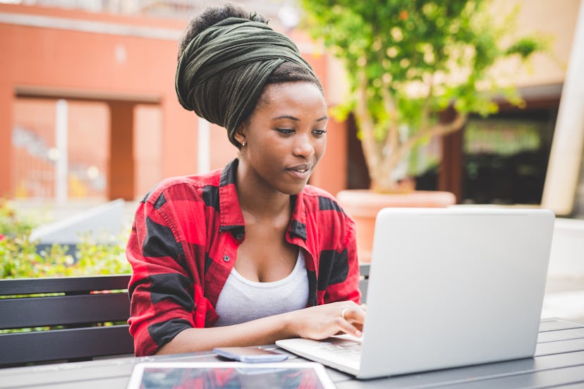 A girl with a turban on her head is working in a park on her laptop