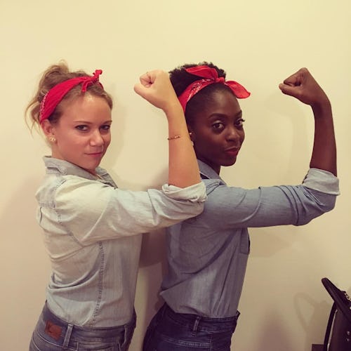 Two women standing beside each other both dressed as and posing as rosie the riveter