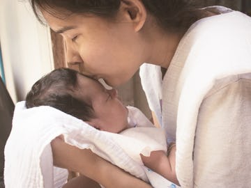 A mom holding her baby and kissing its forehead when she brought the baby home