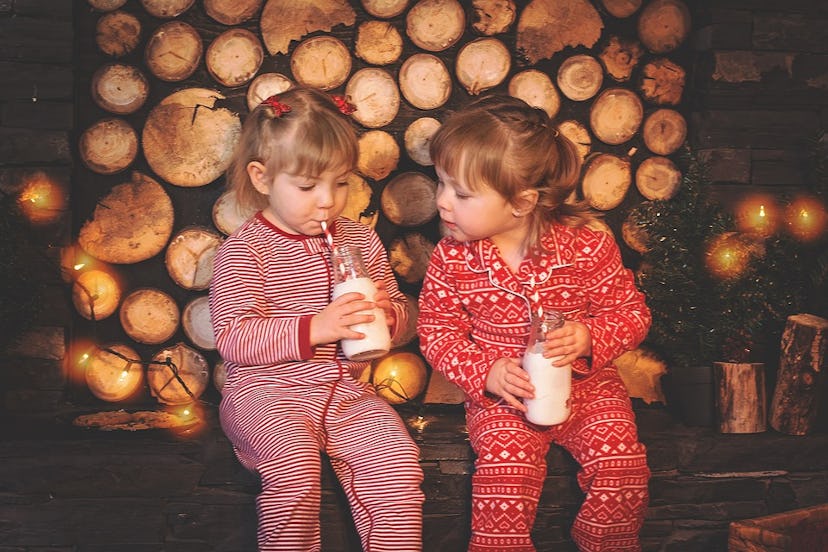 Two small girls drinking milk and wearing Christmas onesies
