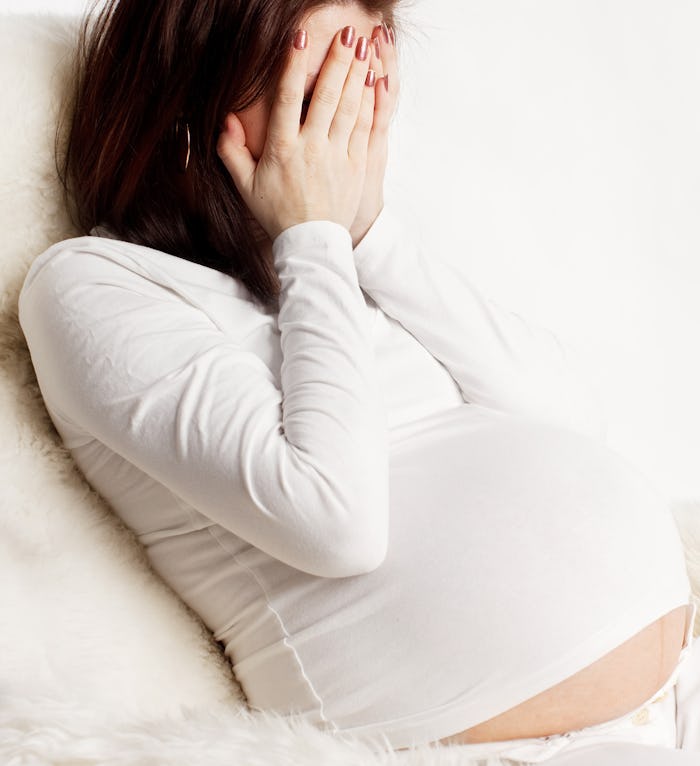 A pregnant woman covering her face with her hands because of struggling with prenatal anxiety