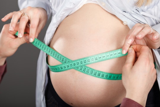 woman measuring pregnant belly with a tape measure