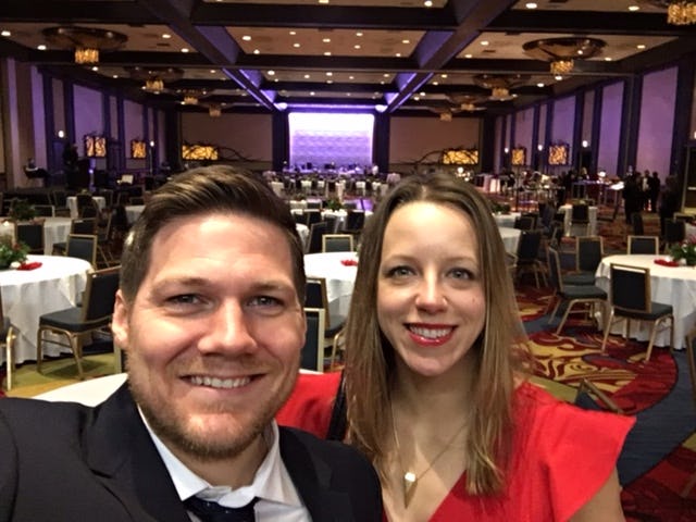 A man and woman dressed up for a formal dinner event taking a selfie 