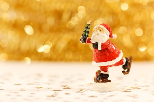 A small ice-skating Santa Clause sculpture carrying a Christmas tree on a white surface