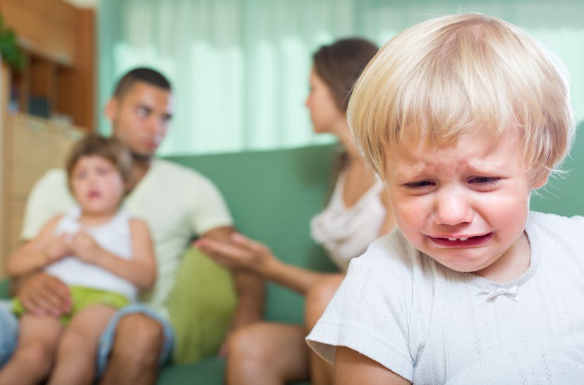 Toddler crying while parents fight behind him