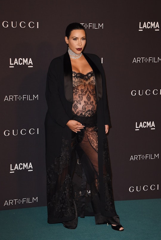 Kim Kardashian pregnant in a black lace dress and a black coat, at a red carpet event