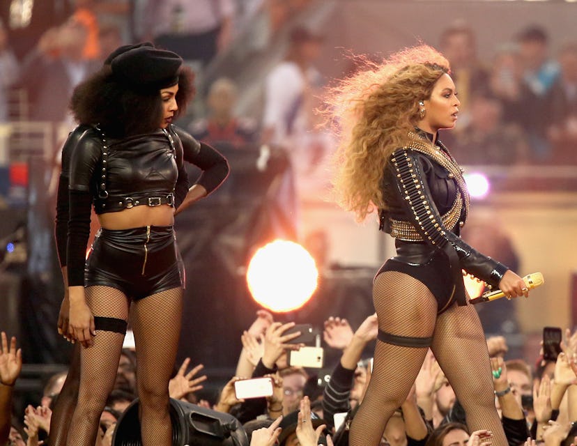 Beyonce at her concert standing on the stage with the same dressed lady
