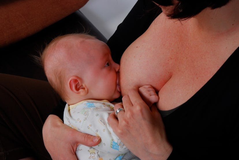 Mother breastfeeding her baby while holding her hand