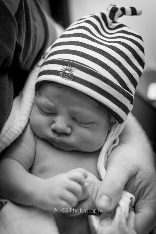 A newborn baby wearing a striped beanie.