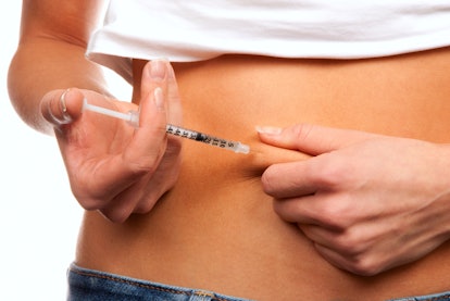 Woman injecting a syringe into her stomach