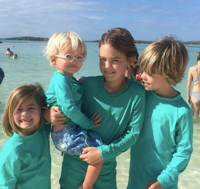 Four children dressed in turquoise shirts posing at a beach