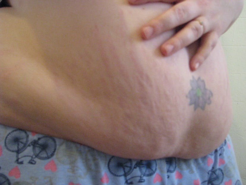 Alternate angle of the fourth week image of Katherine DM Clover with stretch marks and a tattoo of a...