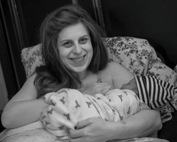A woman sitting in a chair with a floral print holding her newborn baby