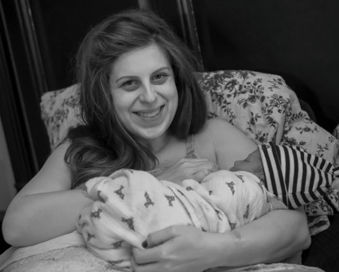 A woman sitting in a chair with a floral print holding her newborn baby
