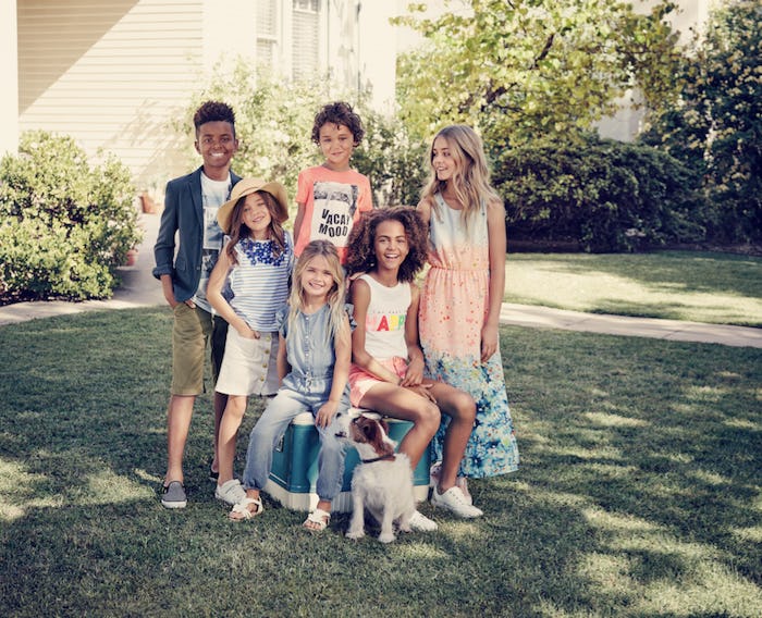 Six kids posing with a dog in the backyard during spring