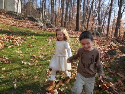 A boy and a girl walking surrounded by trees 