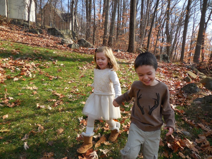 A boy and a girl walking surrounded by trees 