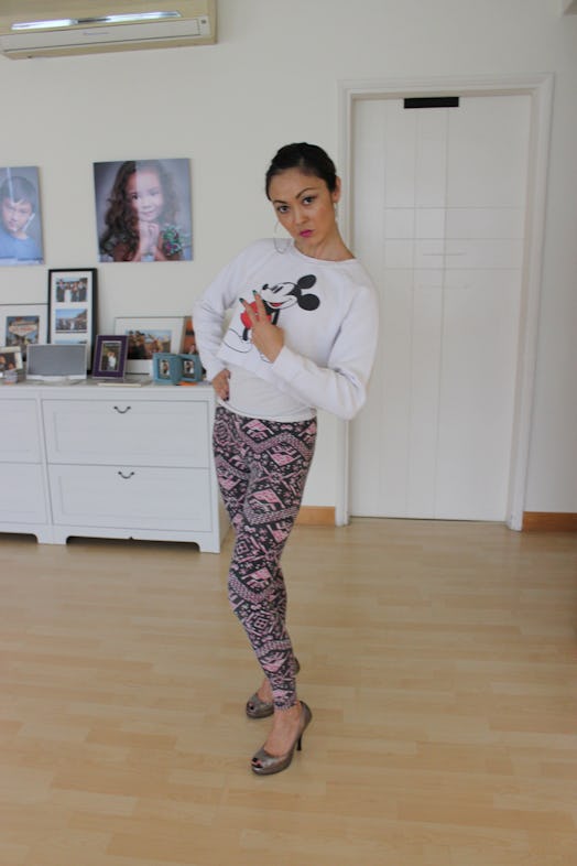 A woman dressed by her 3-year-old in a white Mickey Mouse shirt, multicolored pants and high heels