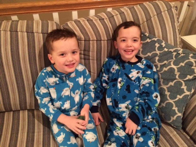 Two boy toddlers sitting on a sofa in their pajamas