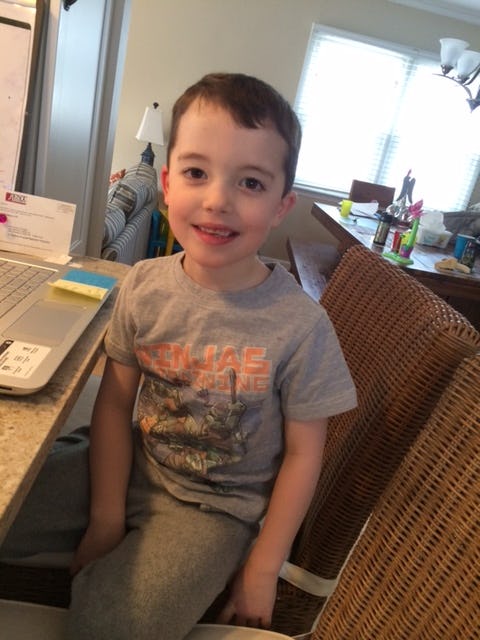 Lee Hayden's son who has a sensory processing disorder sits at a chair and smiles at the camera