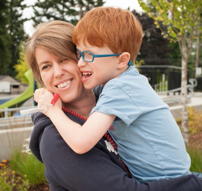 Nikki Mahoney carrying her nonverbal autistic sun in her arms as they both laugh
