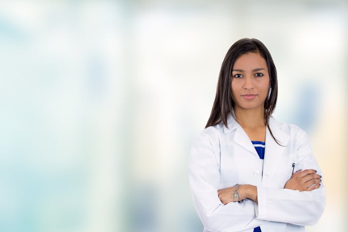 Doctor Amna Dermish standing in white coat with her hands crossed.