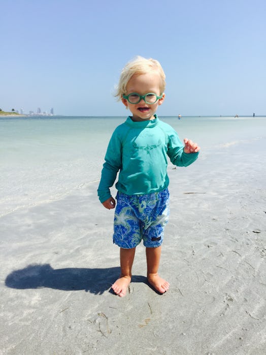 Amos wearing a mint green t-shirt and blue shorts standing at the beach