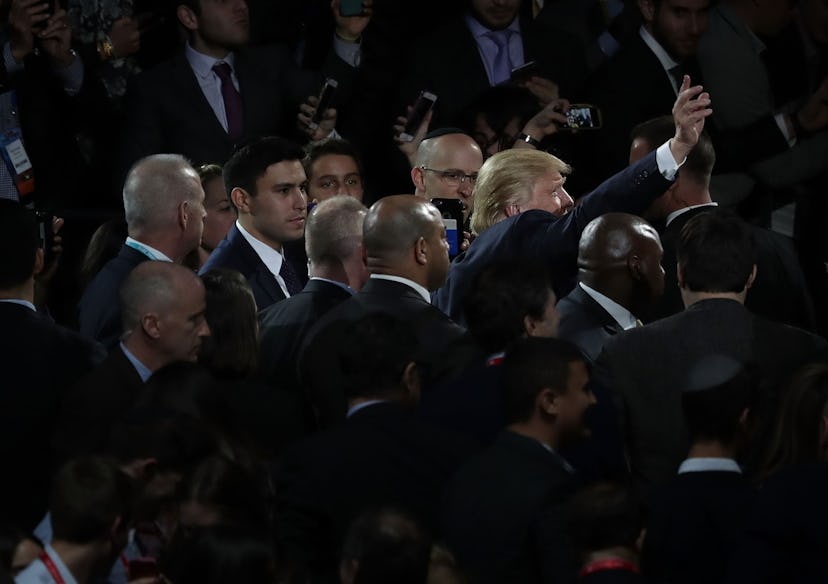 Donald Trump surrounded by men in black suits