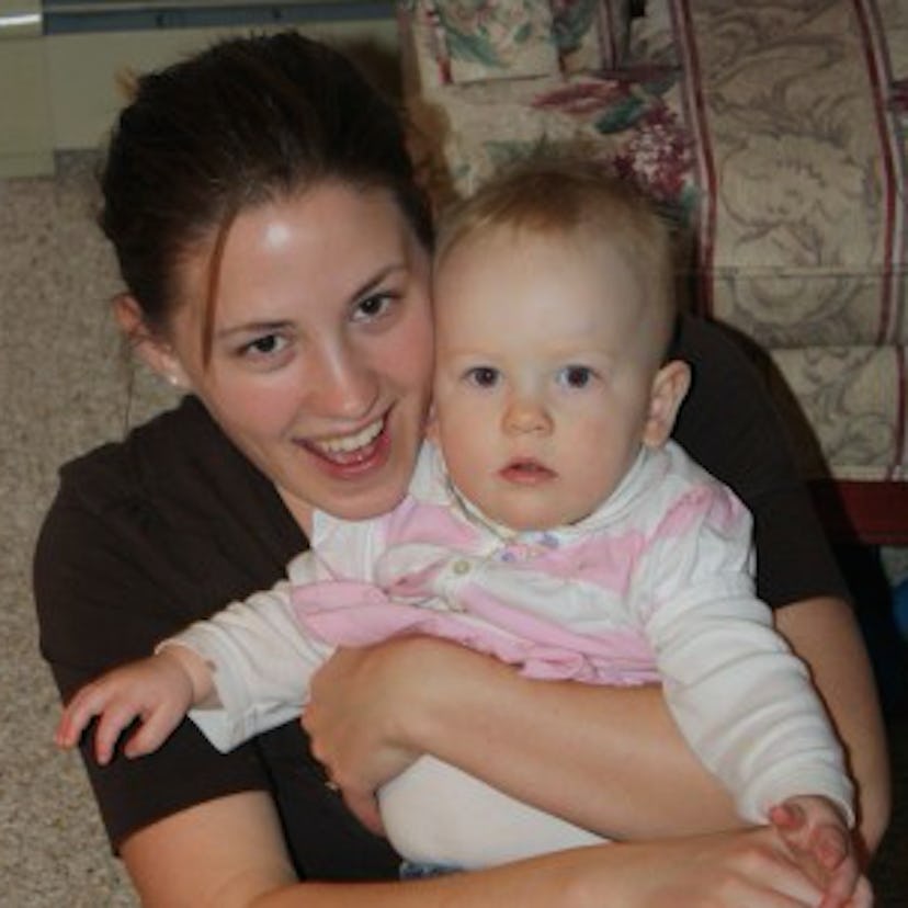 A happy woman hugging a baby wearing a pink and white shirt while posing for a picture.