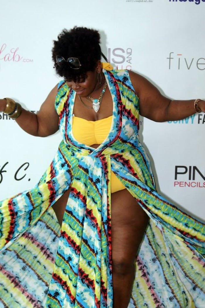 A woman wearing a yellow plus size bathing suit and a green-yellow-mint cape over it