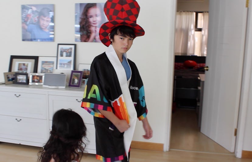 A fashion-obsessed 3-year-old next to her brother wearing a kimono and a red checked hat