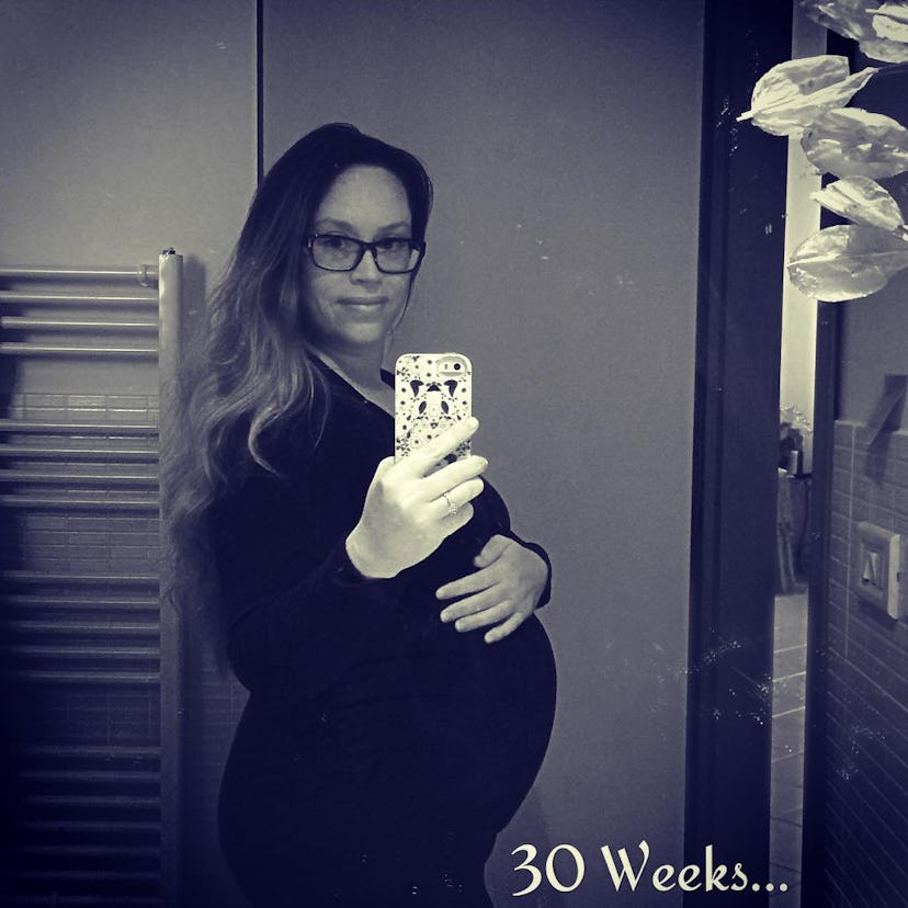 A 30 weeks pregnant woman taking a mirror selfie