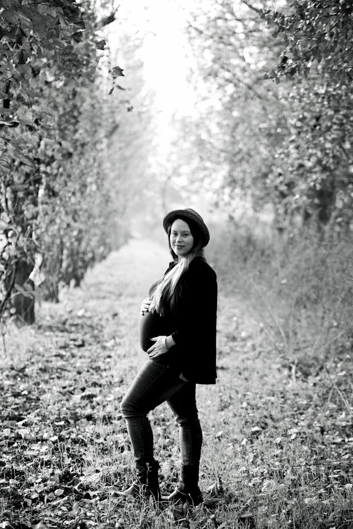 A pregnant fit-shamed mother posing for a photo at a forest road