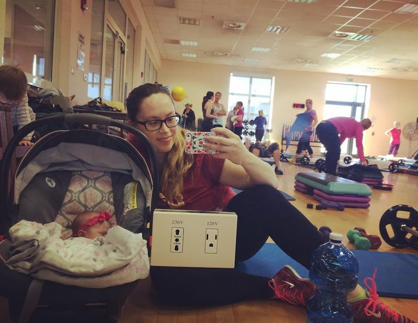 A fit-shamed mother taking a mirror selfie at the gym with her newborn 