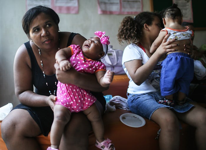 Two mothers with their children checking them for possible Zika rashes