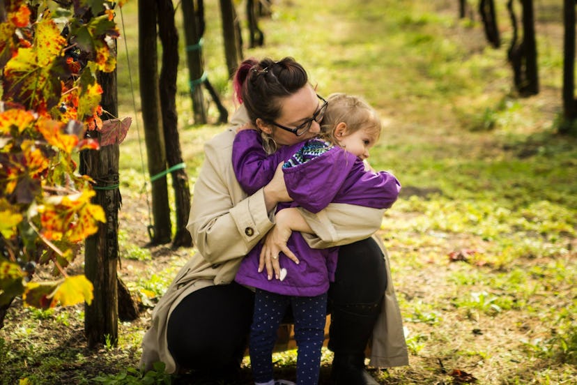 A mother hugging her daughter in a vineyard.