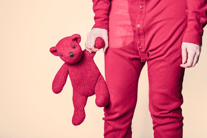 An adult wearing Pexels red onesie while holding a matching teddy bear