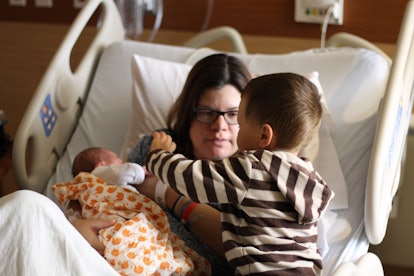 Samantha Taylor in the hospital bed holding her newborn and her son next to them