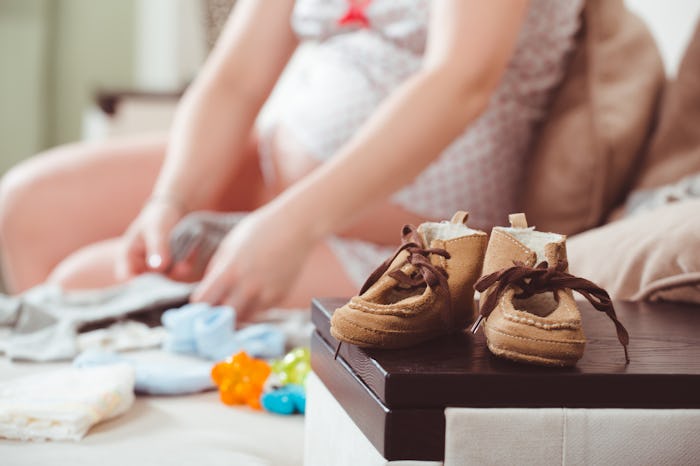 A pregnant woman preparing baby clothes for the baby on the way