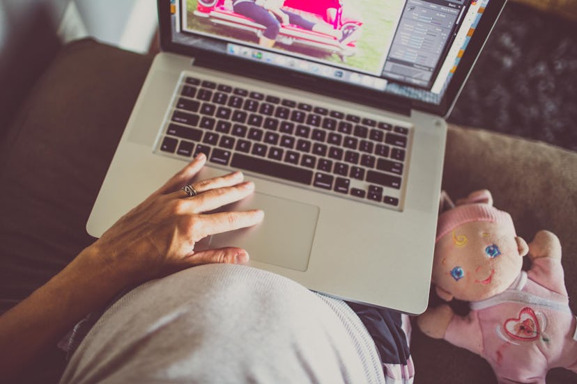 Pregnant work from home mom on her laptop with a doll next to her