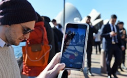 A person playing Pokemon Go in a crowded street