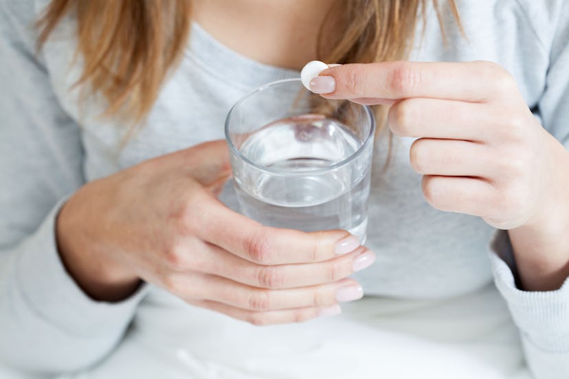 A pregnant woman putting an aspirin tablet in a glass of water to protect herself from Preeclampsia 