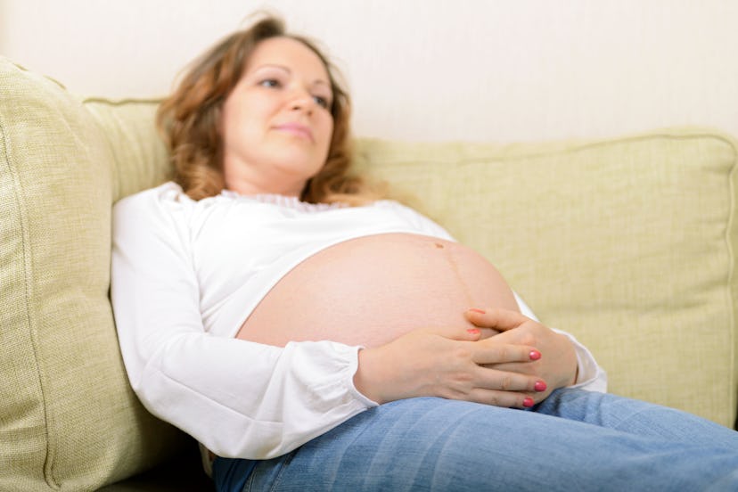 A pregnant woman sitting on a couch with elevated feet to protect herself from Preeclampsia 