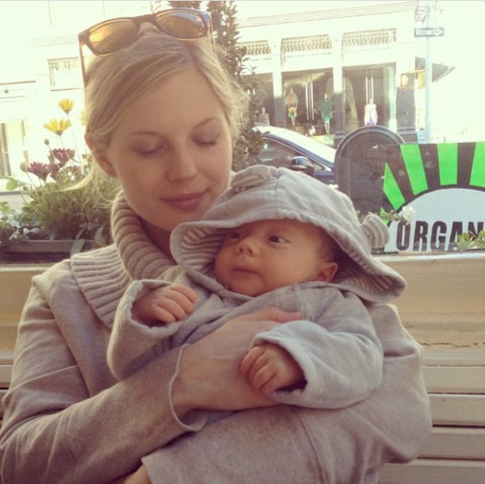 A woman holding her baby while sitting on a bench