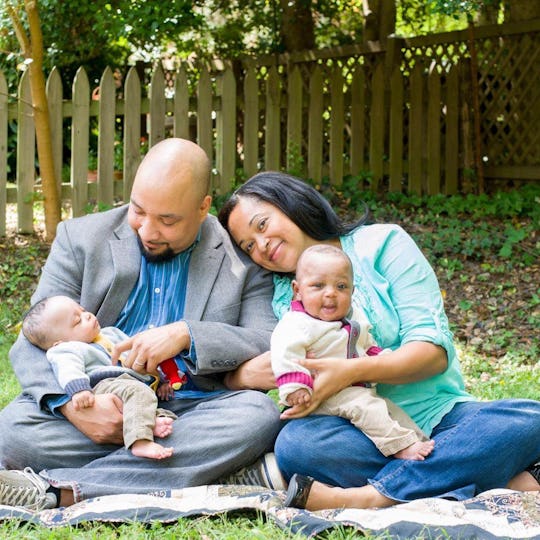 A family of parents and two baby boys posing for a photo in their garden