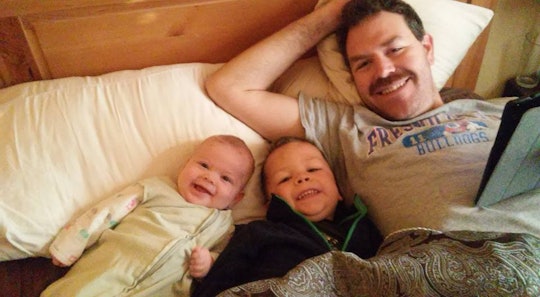 A dad in the bed with his two little sons.