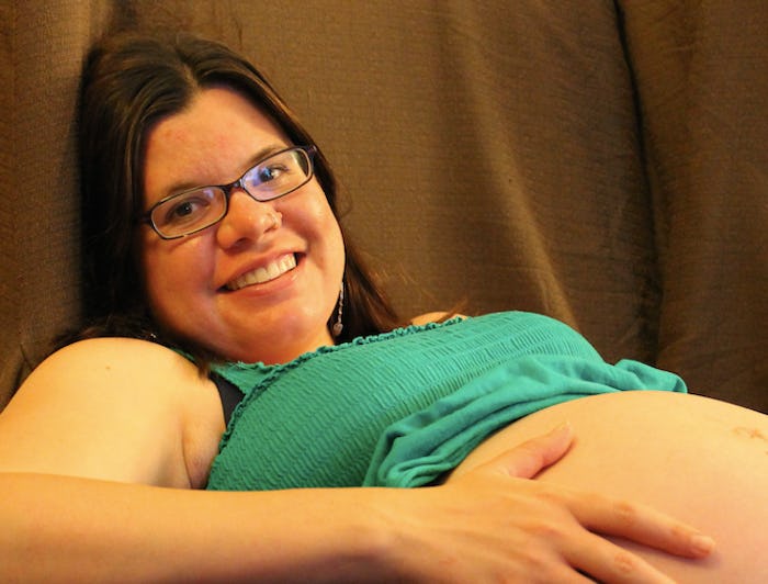 Samantha Taylor, smiling and lying on her back in a green top while holding her hand on her pregnant...